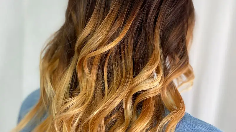 Curly hair with a warm caramel-to-blonde balayage