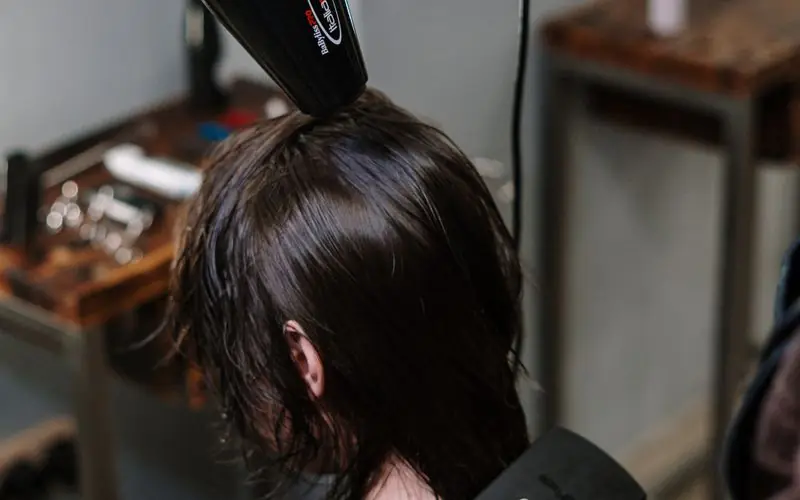 Stylist blow-drying a client’s dark bob