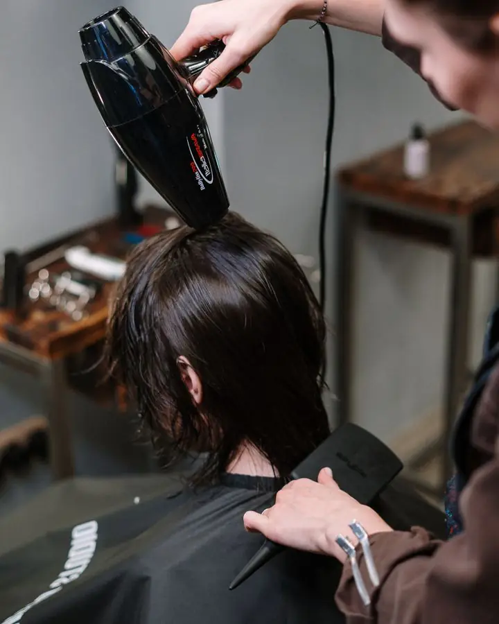 Stylist blow-drying a client’s dark bob
