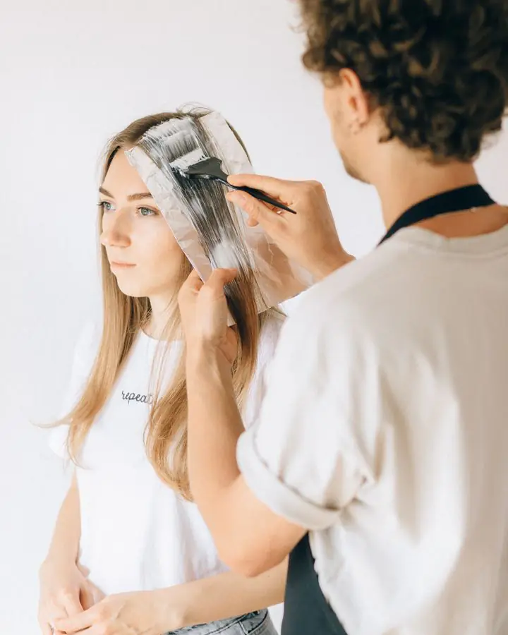 Colourist painting lightener onto sections of hair