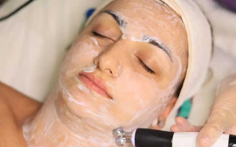 HydraFacial wand gliding over a client’s cheek