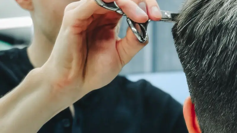 Barber cutting a man’s hair with scissors