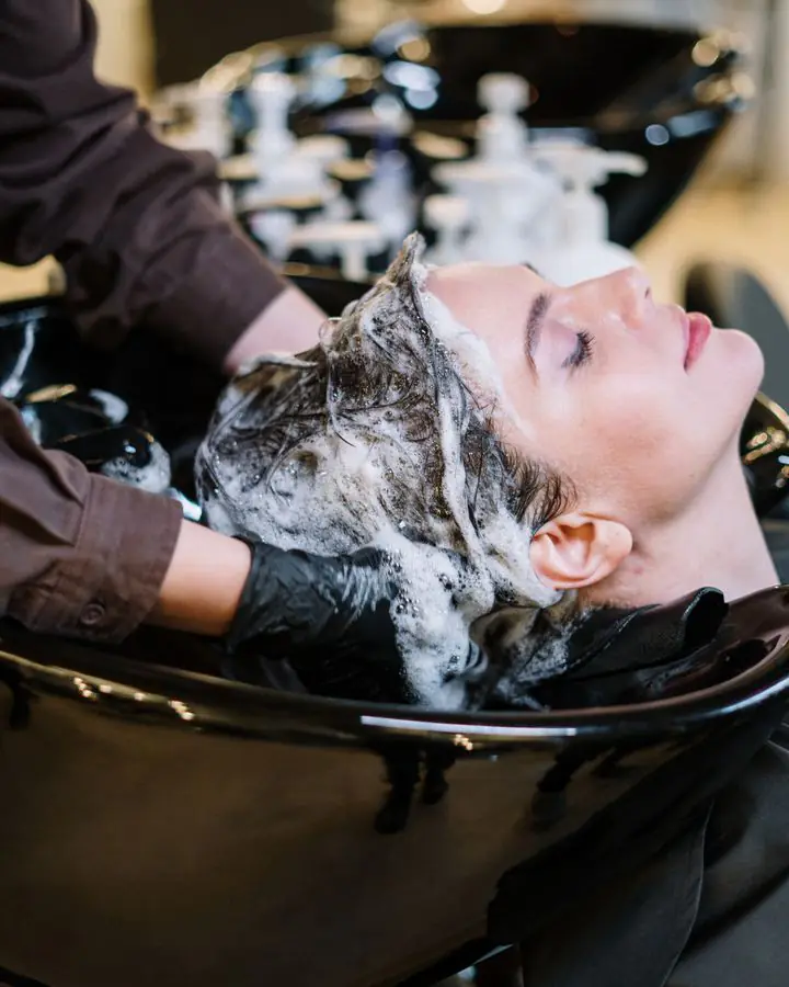 Stylist washing a client’s hair at the basin